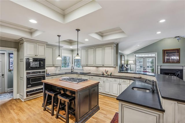 kitchen featuring kitchen peninsula, black appliances, a tray ceiling, and wood counters