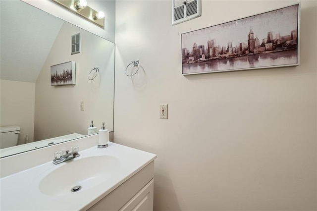 bathroom featuring toilet, lofted ceiling, and vanity