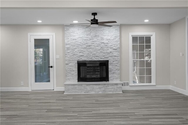 unfurnished living room with a fireplace, wood-type flooring, and ceiling fan