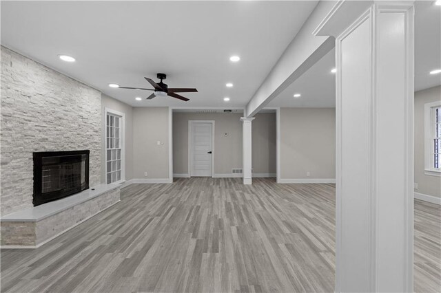 unfurnished living room with ceiling fan, a fireplace, and light hardwood / wood-style floors