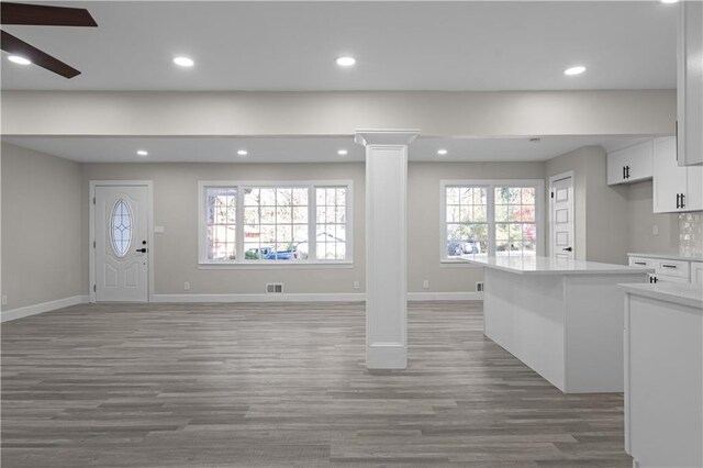 unfurnished living room with hardwood / wood-style floors, plenty of natural light, ceiling fan, and decorative columns