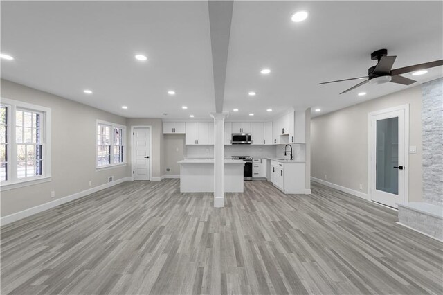 unfurnished living room featuring light wood-type flooring, ceiling fan, and sink