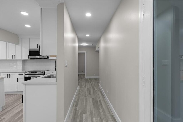 corridor featuring light hardwood / wood-style flooring and sink