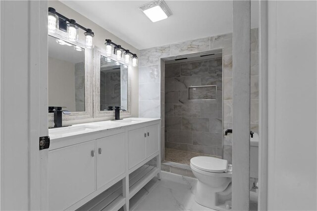 bathroom featuring a tile shower, vanity, and toilet