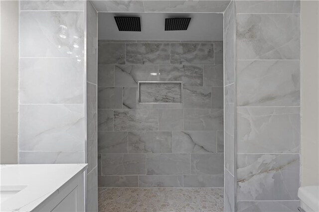 bathroom with vanity, toilet, and tiled shower