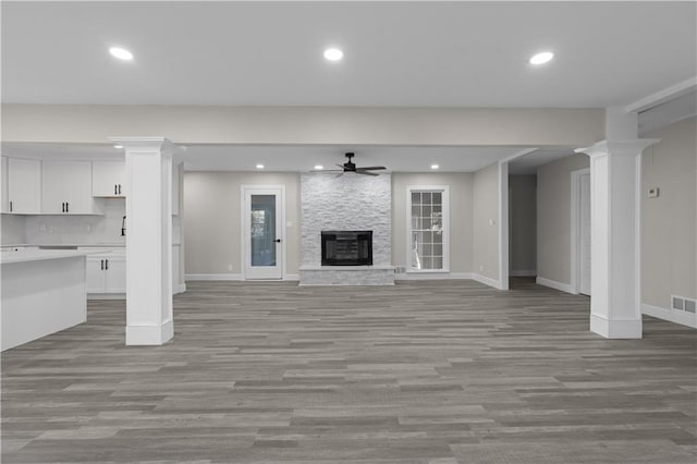 unfurnished living room featuring a stone fireplace, ceiling fan, and light wood-type flooring