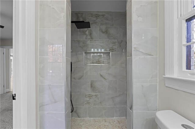 bathroom featuring tiled shower and toilet