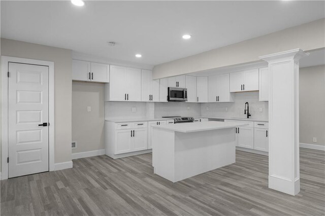 kitchen featuring white cabinets, a center island, stainless steel appliances, and sink