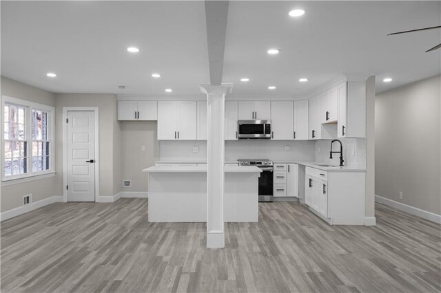 kitchen featuring white cabinetry, sink, light hardwood / wood-style floors, and appliances with stainless steel finishes