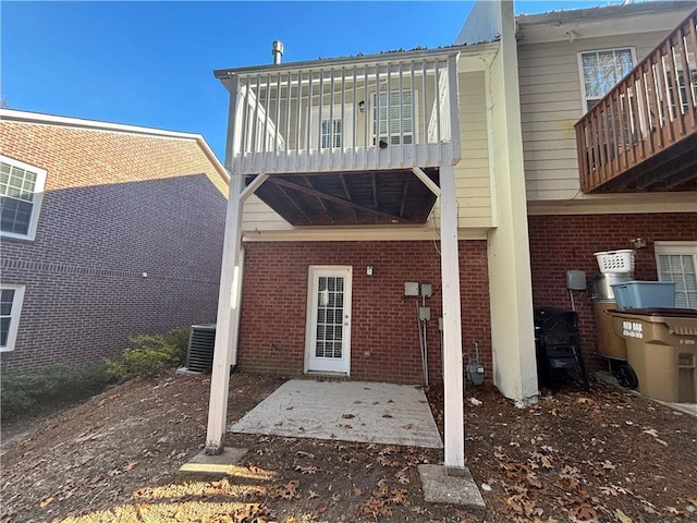 rear view of property with a balcony, a patio, and central AC