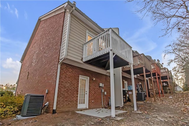 rear view of property featuring a balcony, a patio area, and central air condition unit