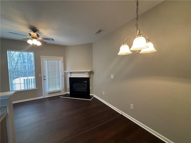 unfurnished living room with ceiling fan with notable chandelier and dark hardwood / wood-style floors