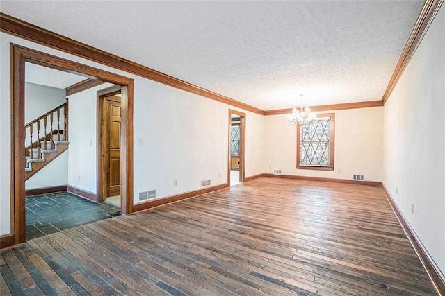 empty room featuring a textured ceiling, dark hardwood / wood-style floors, ornamental molding, and an inviting chandelier