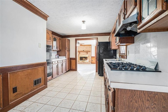 kitchen with a fireplace, black double oven, a textured ceiling, and stainless steel gas stovetop