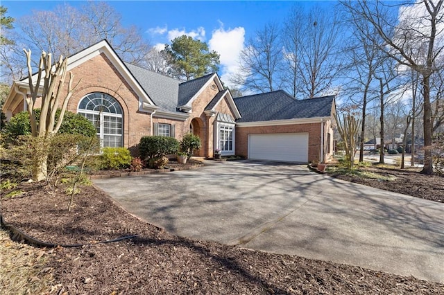 view of front of home featuring concrete driveway, an attached garage, brick siding, and roof with shingles