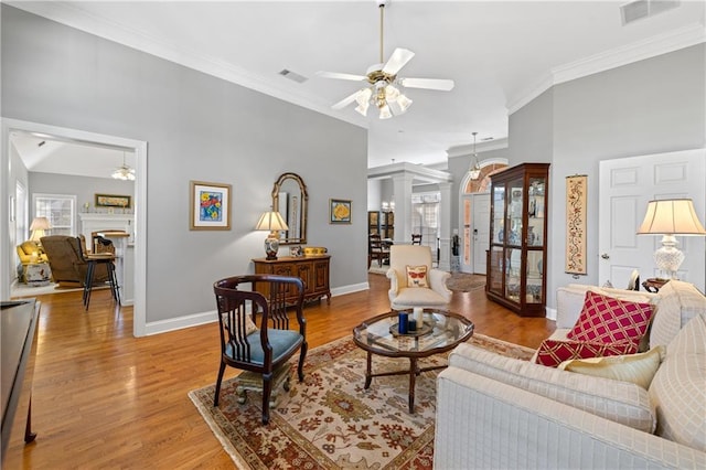 living area with visible vents, wood finished floors, a ceiling fan, and crown molding