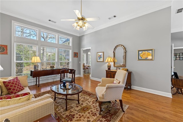 living area with visible vents, ornamental molding, and wood finished floors