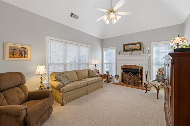 living room with visible vents, light colored carpet, vaulted ceiling, a fireplace, and a ceiling fan