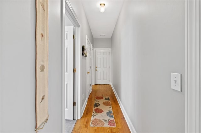 hallway featuring light wood-type flooring and baseboards