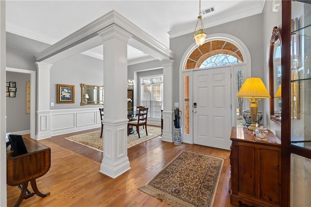 entryway with visible vents, crown molding, ornate columns, and wood finished floors