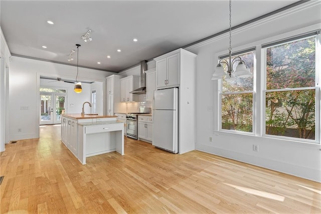 kitchen with decorative light fixtures, white fridge, white cabinetry, and stainless steel gas range