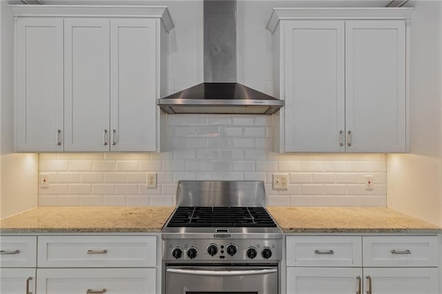 kitchen featuring high end stove, white cabinetry, and wall chimney exhaust hood