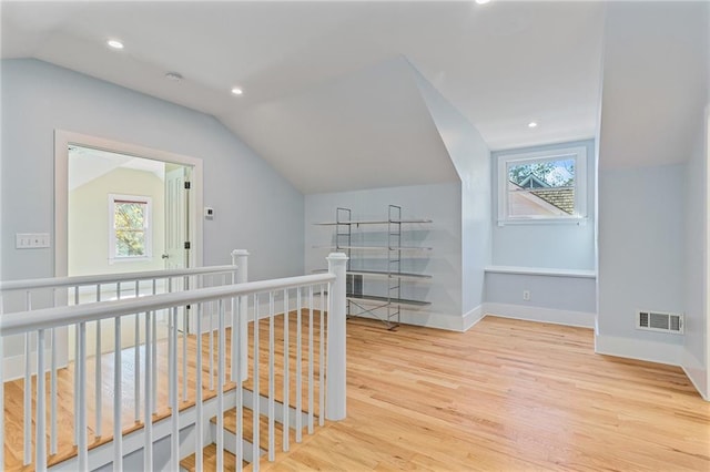 hall with vaulted ceiling, a wealth of natural light, and light hardwood / wood-style flooring