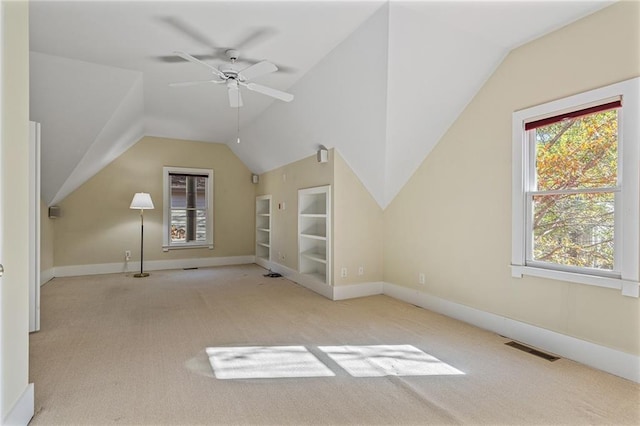 additional living space with built in shelves, ceiling fan, light colored carpet, and lofted ceiling