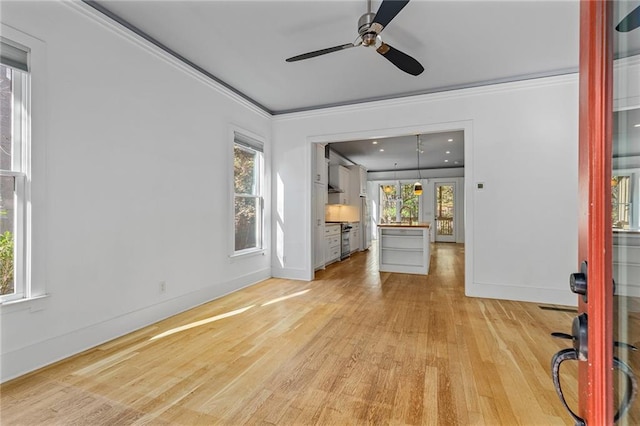 unfurnished living room with a healthy amount of sunlight, ornamental molding, and light hardwood / wood-style flooring