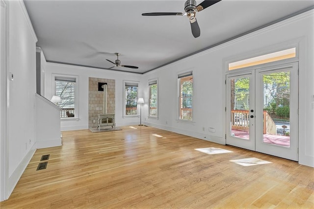 unfurnished living room featuring a wood stove, french doors, crown molding, ceiling fan, and light hardwood / wood-style floors