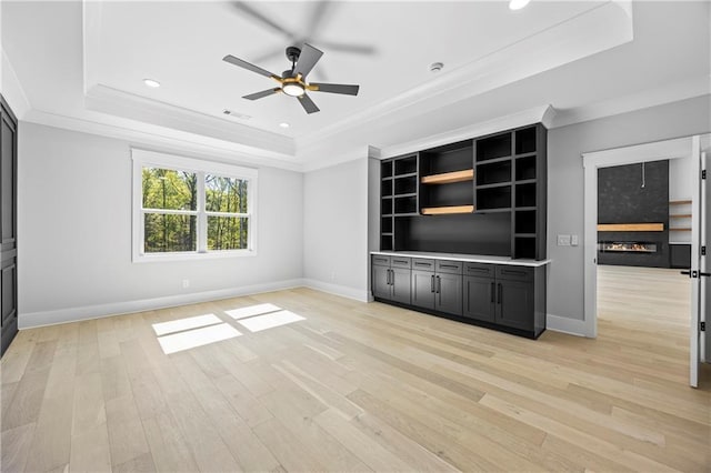 6238 Mount Salem Cir, Flowery Branch, GA 30542 - unfurnished living room featuring a tray ceiling, a glass covered fireplace, a ceiling fan, ornamental molding, and light wood finished floors