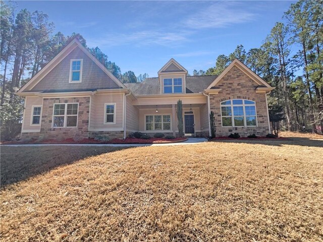 craftsman house featuring stone siding and a front lawn