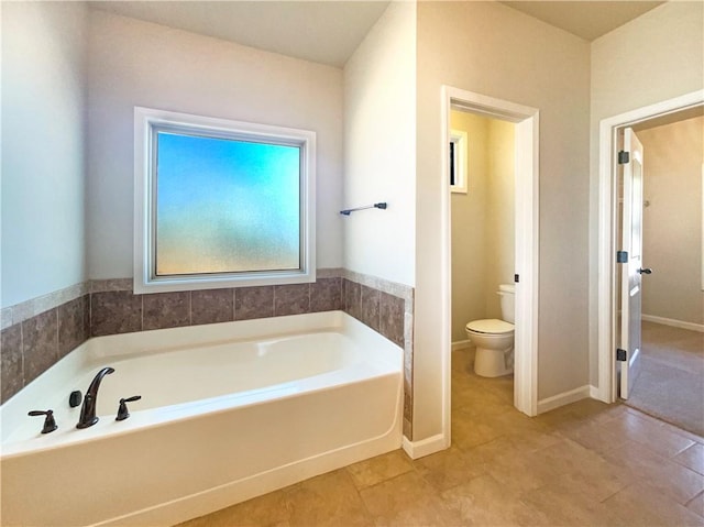 full bathroom featuring a bath, tile patterned flooring, toilet, and baseboards