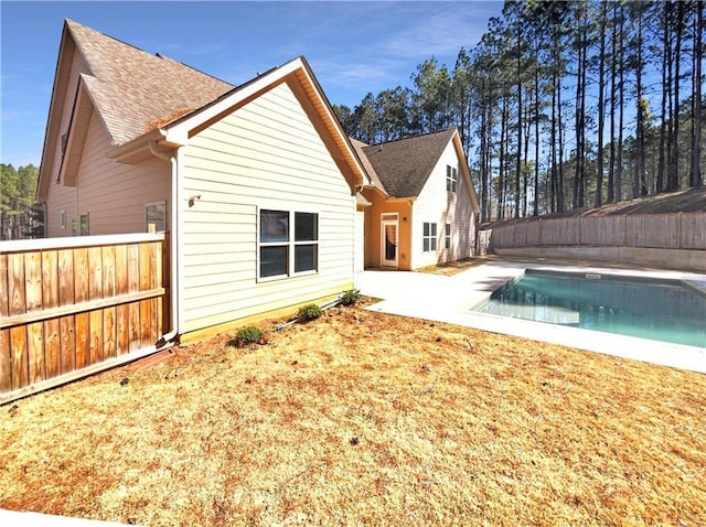 back of property featuring a fenced in pool, roof with shingles, a fenced backyard, and a patio area