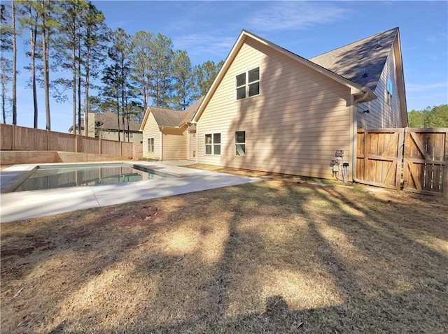 rear view of property featuring a patio, a gate, a fenced backyard, and a fenced in pool