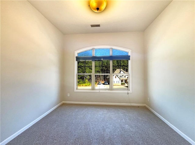 spare room with carpet flooring, baseboards, and visible vents