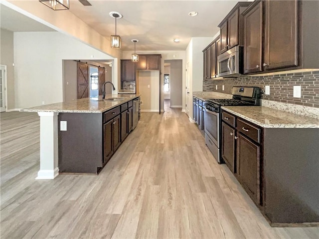 kitchen featuring a sink, stainless steel appliances, tasteful backsplash, and light wood finished floors