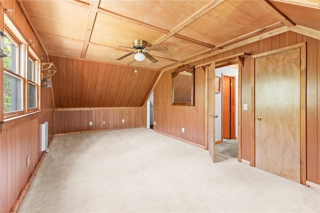 additional living space featuring wooden walls, light colored carpet, a ceiling fan, and lofted ceiling