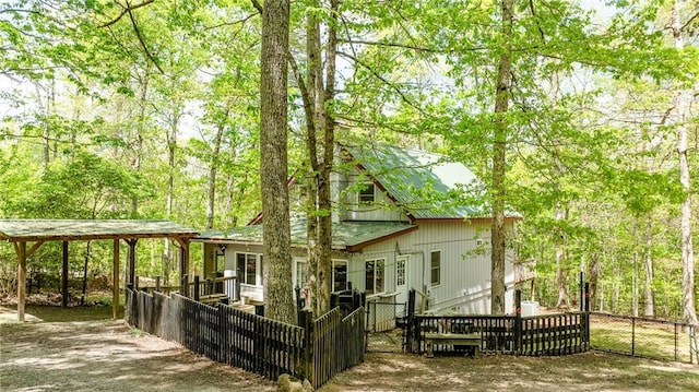 rear view of house with a gate, fence private yard, a detached carport, and metal roof