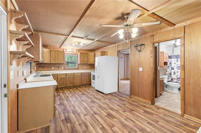 kitchen featuring wooden walls, light countertops, light wood-type flooring, and white appliances