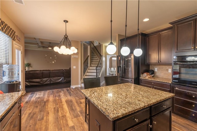 kitchen featuring black oven, dark brown cabinets, stainless steel refrigerator with ice dispenser, a kitchen island, and decorative light fixtures