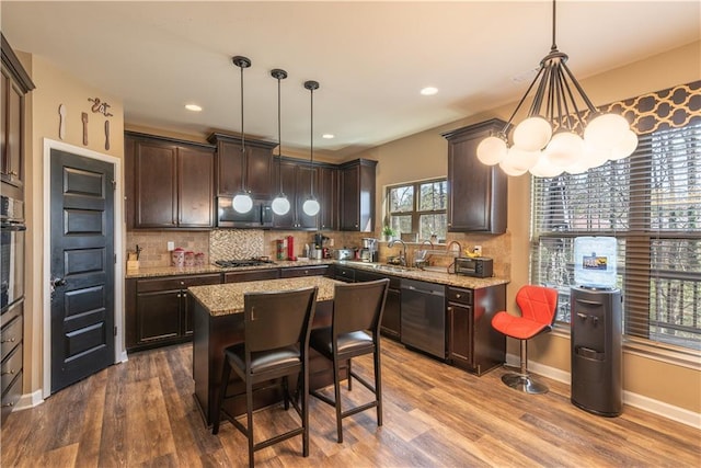kitchen with hanging light fixtures, dark brown cabinets, a center island, and appliances with stainless steel finishes
