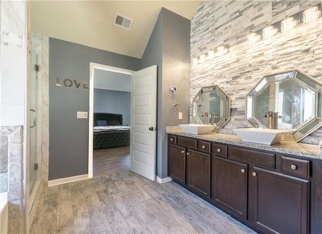 bathroom featuring vanity, a shower with shower door, vaulted ceiling, and wood-type flooring