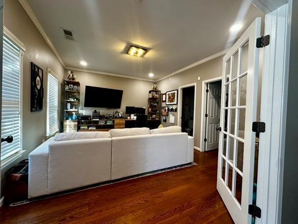 living room featuring dark wood-type flooring, ornamental molding, french doors, and a wealth of natural light