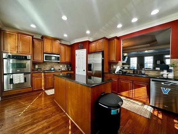 kitchen with dark hardwood / wood-style flooring, crown molding, stainless steel appliances, and a center island