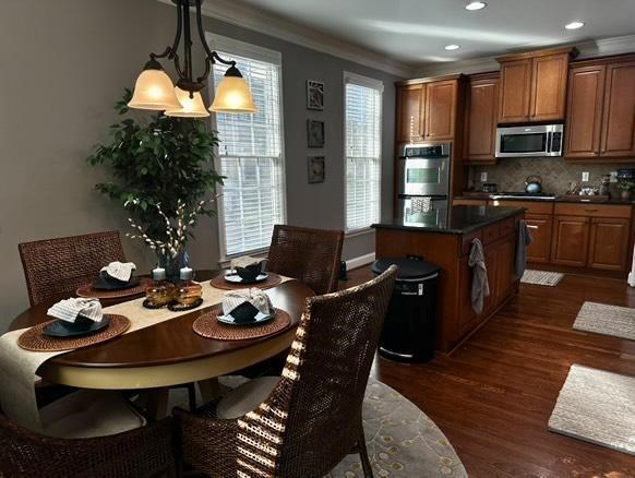 dining space featuring ornamental molding and dark hardwood / wood-style flooring