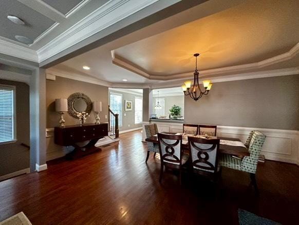 dining space featuring dark hardwood / wood-style flooring, ornamental molding, a raised ceiling, and a chandelier