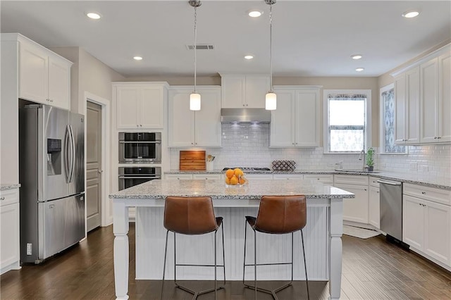 13015 Fox Rd, Alpharetta, GA 30005 - kitchen with stainless steel appliances, under cabinet range hood, white cabinets, a breakfast bar area, and recessed lighting