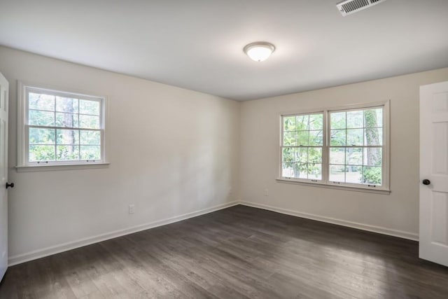 spare room featuring baseboards and dark wood-type flooring