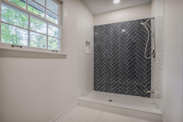 bathroom with a tile shower and baseboards